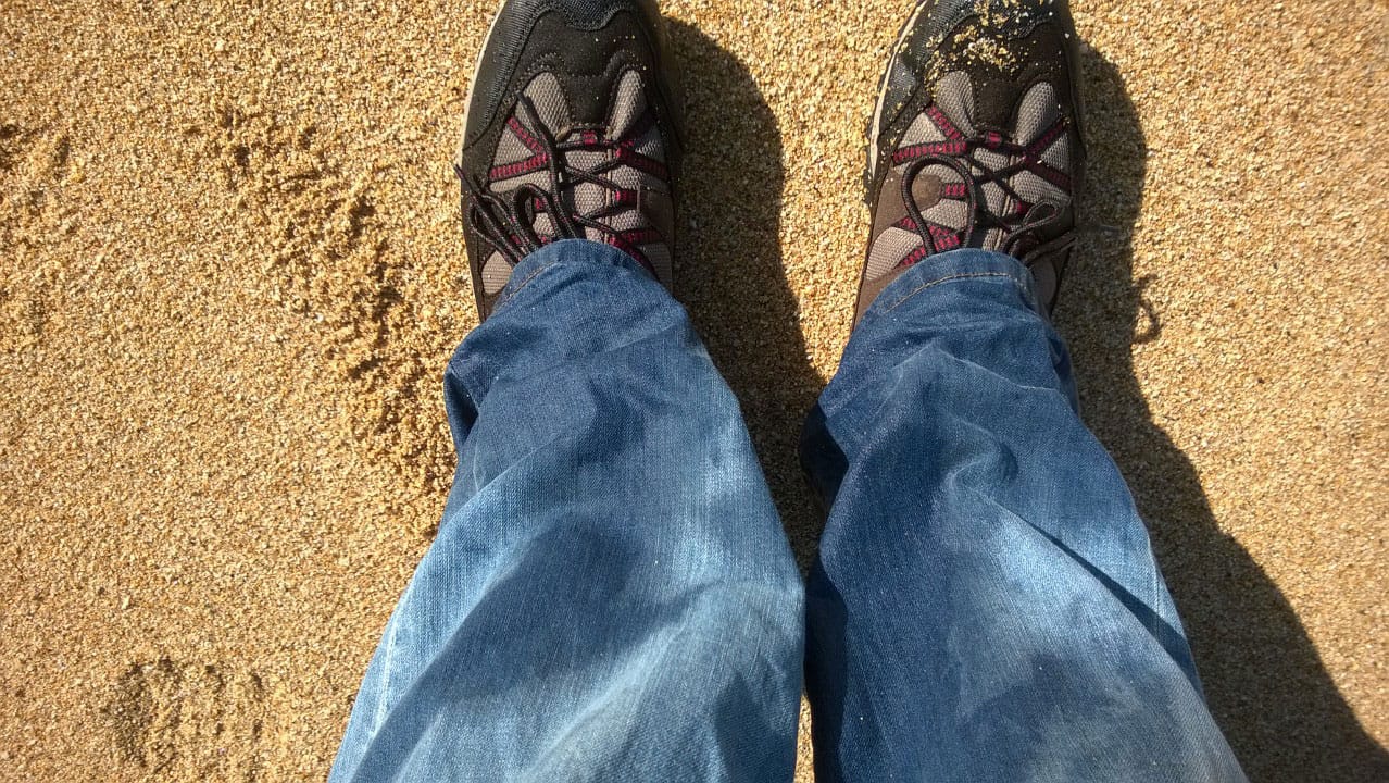 Wet boots and jeans on the sand of a beach