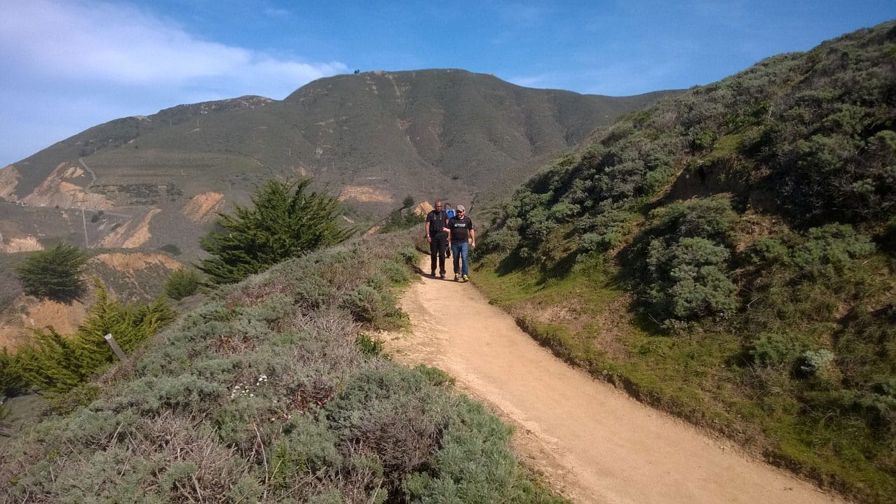 Two men hiking down a mountain trail from the north