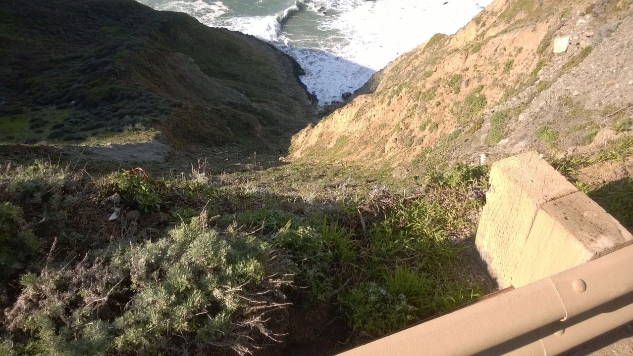 A photo down the side of a cliff towards the ocean.