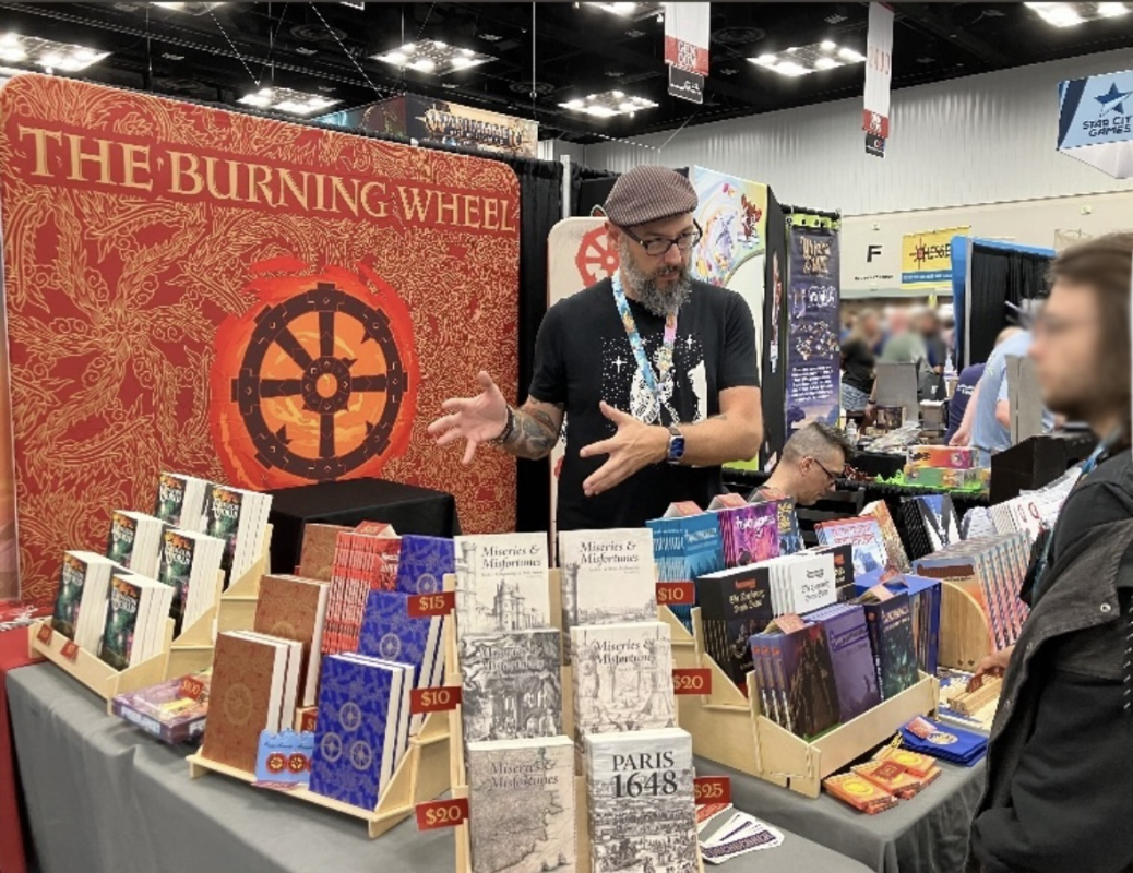 Keith Senkowski discussing Torchbearer at the Burning Wheel booth at GenCon 2024